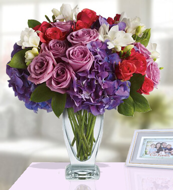 8 Purple Roses, 8 Red Roses, 3 stems White Chrysanthemum, 1 stems White Lily, 2 Blue Hydrangea in a Glass Vase (one sided round arrangement) Affection