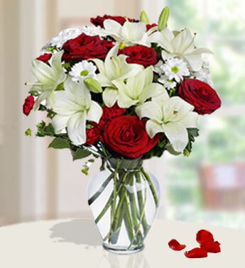 4 Red Roses, 6 Red Carnations, 5 stems of White Lilies & 2 White Chrysanthemum in a glass vase. (one sided round arrangement) Jumping For Joy