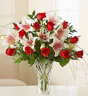 12 Red Roses and 4 stems of Pink Lilies in a glass vase. Source of Grace